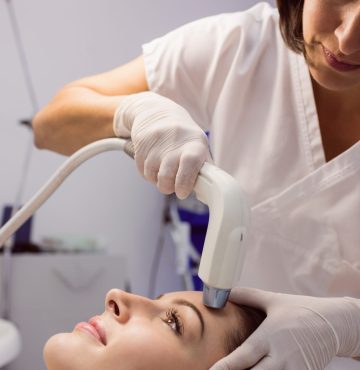 Doctor giving cosmetic treatment to female patient at clinic